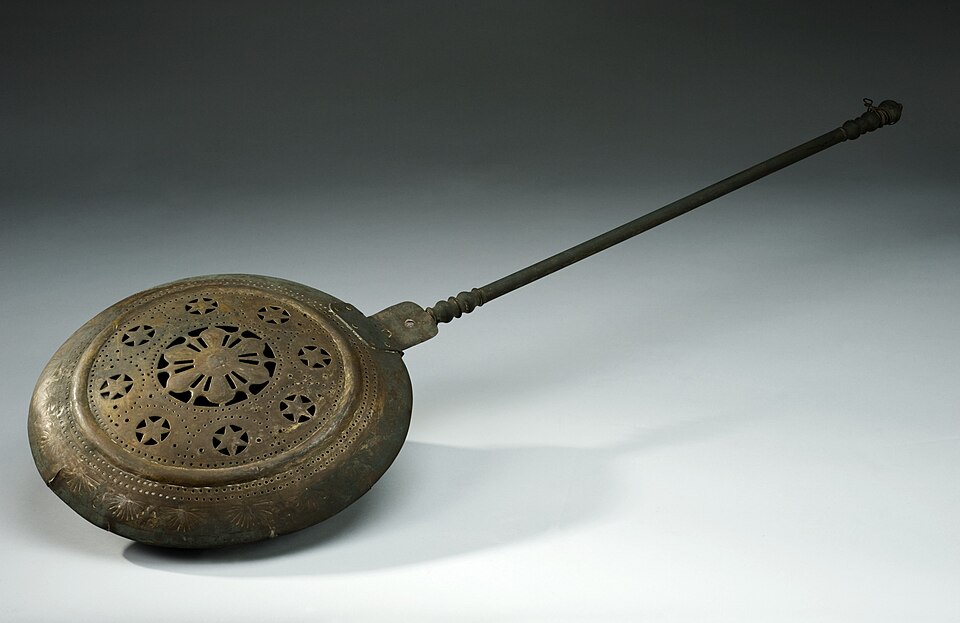 Image of a brass warming pan to warm beds with hot coals.